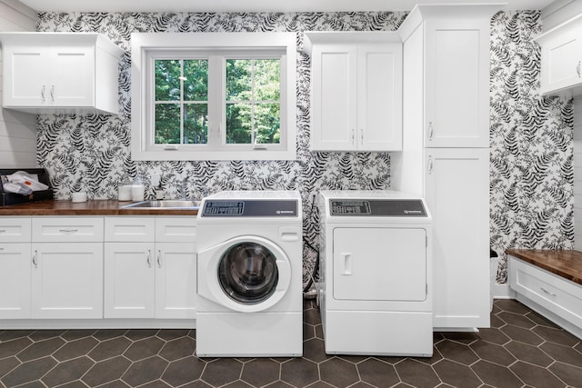 washroom featuring cabinet space, dark tile patterned flooring, washer and clothes dryer, and a sink