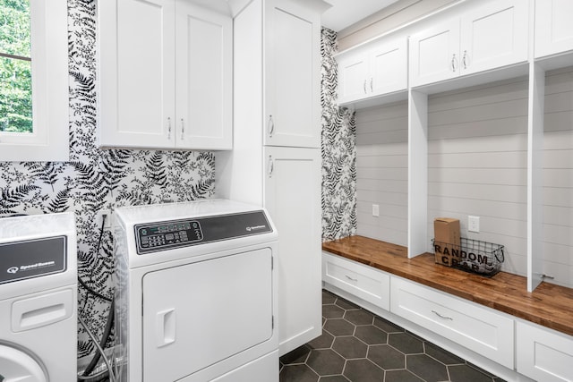 clothes washing area with dark tile patterned floors, independent washer and dryer, and cabinet space