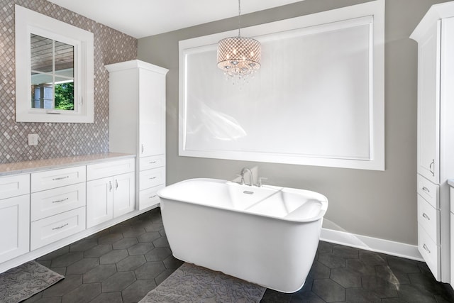 full bathroom featuring a freestanding tub, vanity, baseboards, tile patterned flooring, and decorative backsplash