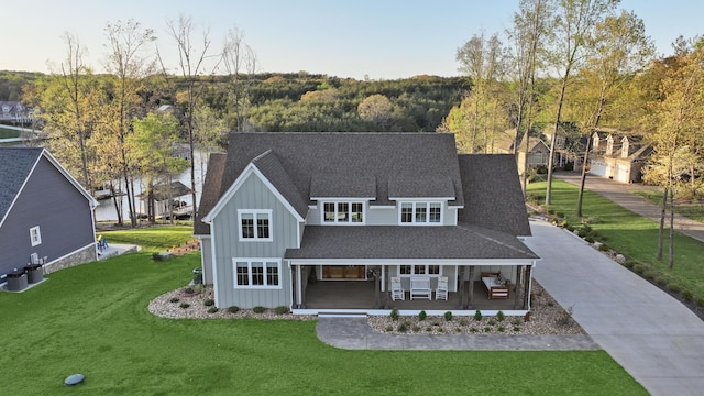 view of front of home with a porch, board and batten siding, a shingled roof, and a front yard