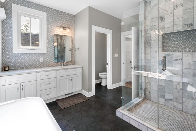 full bath with toilet, vanity, baseboards, and a stall shower