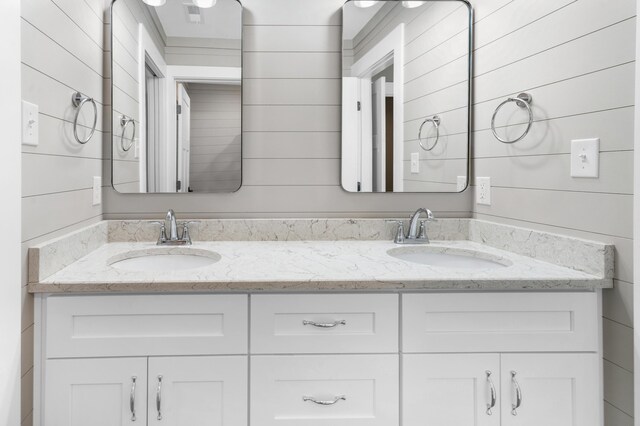 bathroom with wooden walls, a sink, and visible vents