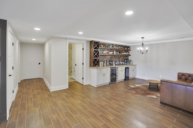 bar with wood finished floors, recessed lighting, beverage cooler, and indoor bar