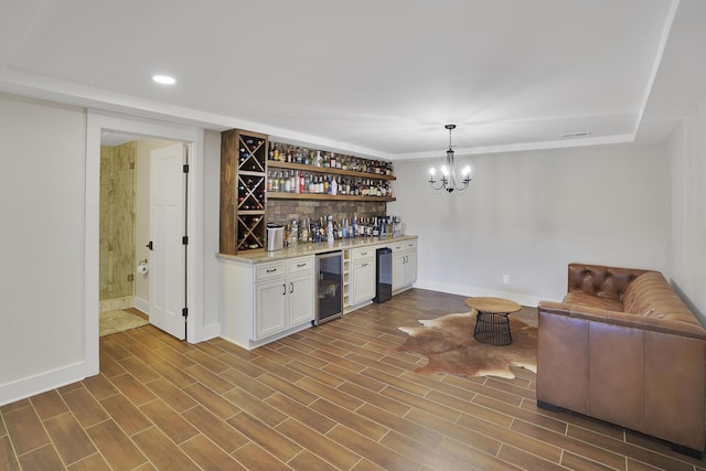 bar featuring a notable chandelier, dark wood-style flooring, a dry bar, and wine cooler
