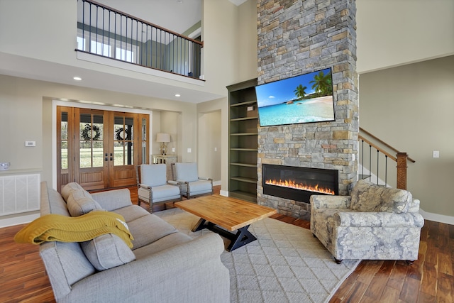 living room featuring baseboards, built in features, a fireplace, visible vents, and wood finished floors