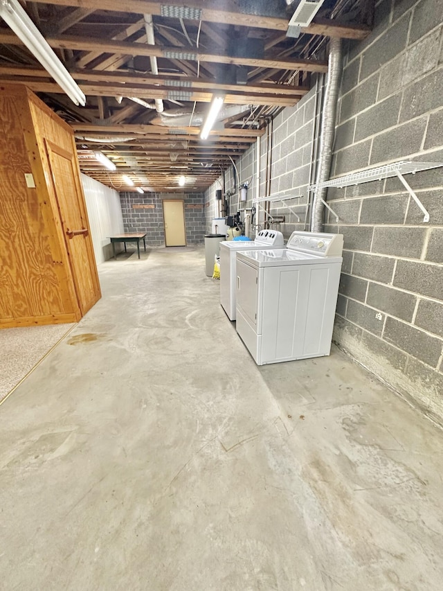 unfinished below grade area featuring concrete block wall and washing machine and dryer