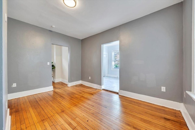 spare room with baseboards and light wood-type flooring