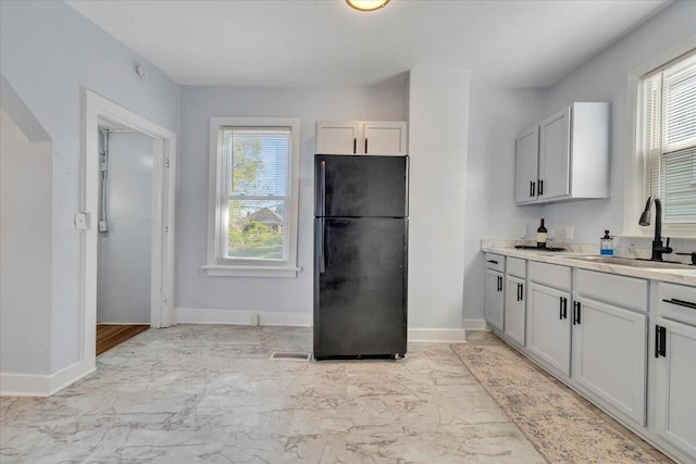 kitchen with a wealth of natural light, marble finish floor, a sink, and freestanding refrigerator