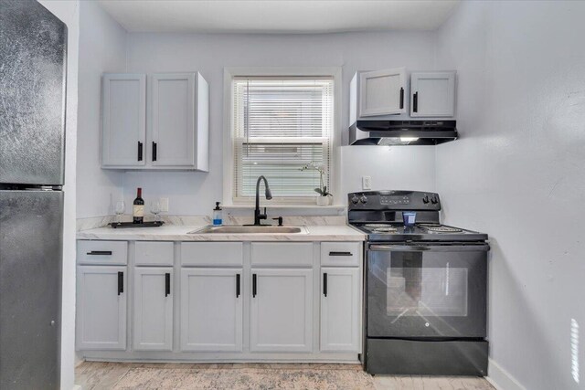 kitchen with black appliances, under cabinet range hood, light countertops, a sink, and baseboards