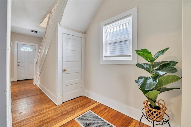 entrance foyer featuring visible vents, light wood-type flooring, baseboards, and lofted ceiling