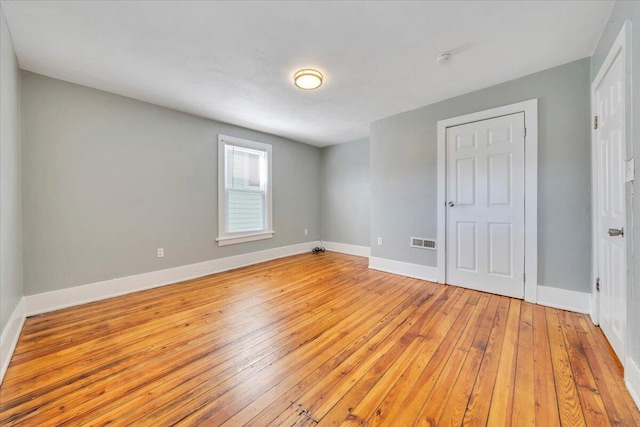 unfurnished bedroom with visible vents, light wood-style flooring, and baseboards