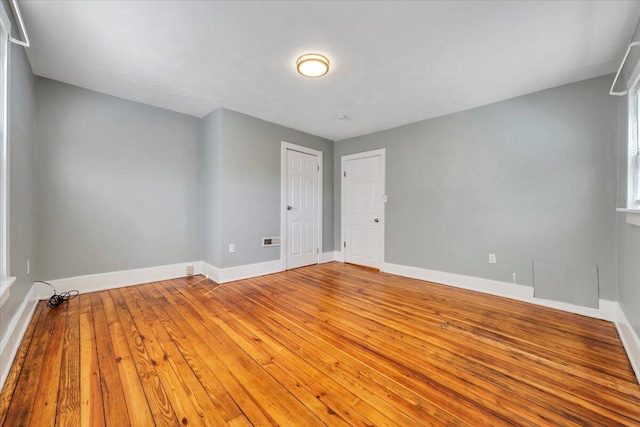 empty room with visible vents, baseboards, and hardwood / wood-style flooring
