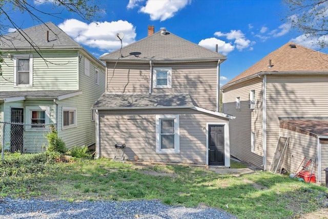 back of house with fence, a lawn, and roof with shingles