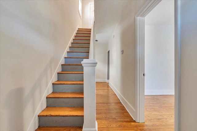staircase featuring wood finished floors and baseboards