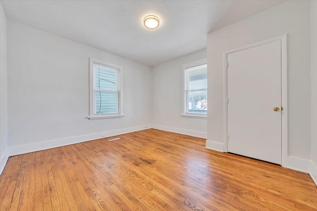 empty room with light wood-type flooring, baseboards, and visible vents