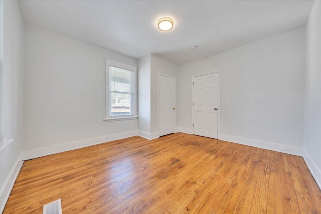 spare room featuring light wood-style floors, visible vents, and baseboards