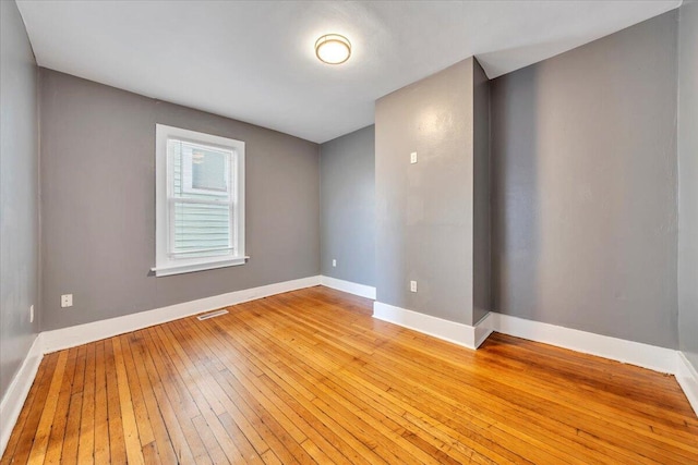 spare room with baseboards, visible vents, and hardwood / wood-style flooring