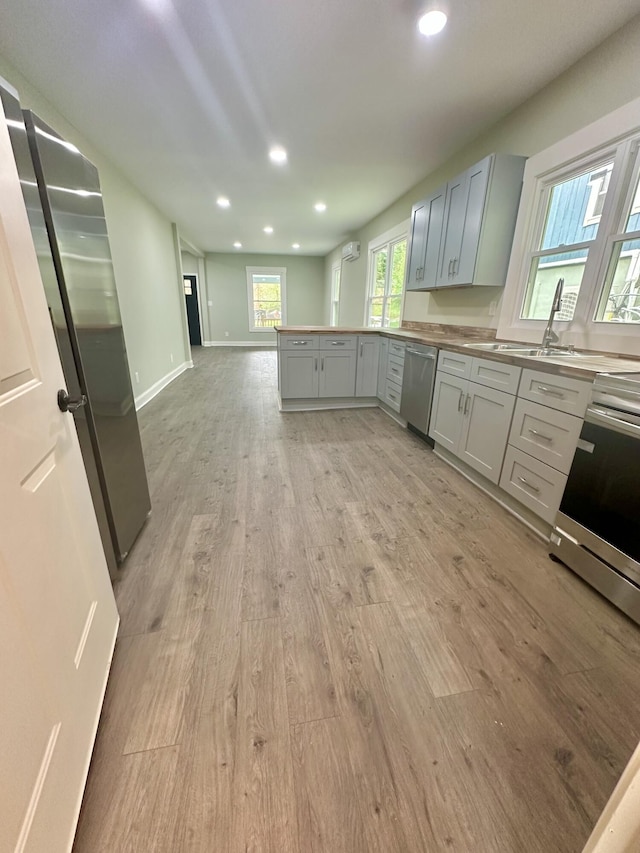 kitchen with stainless steel appliances, light wood-style flooring, a peninsula, baseboards, and recessed lighting