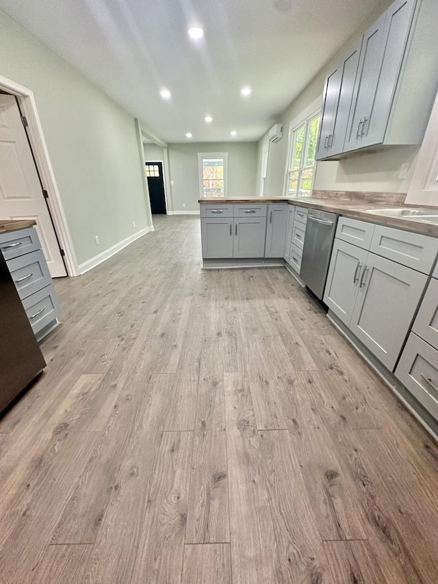 kitchen featuring dishwasher, gray cabinets, light wood finished floors, a peninsula, and recessed lighting