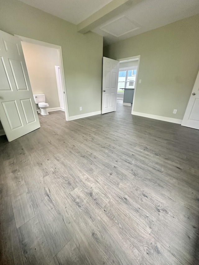 interior space featuring attic access, baseboards, and wood finished floors