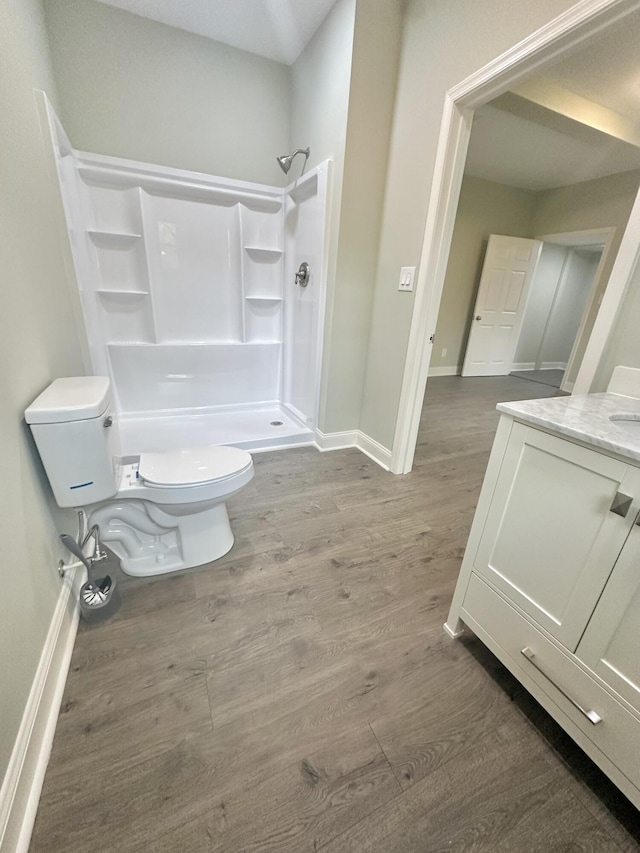 full bathroom featuring baseboards, toilet, a stall shower, and wood finished floors
