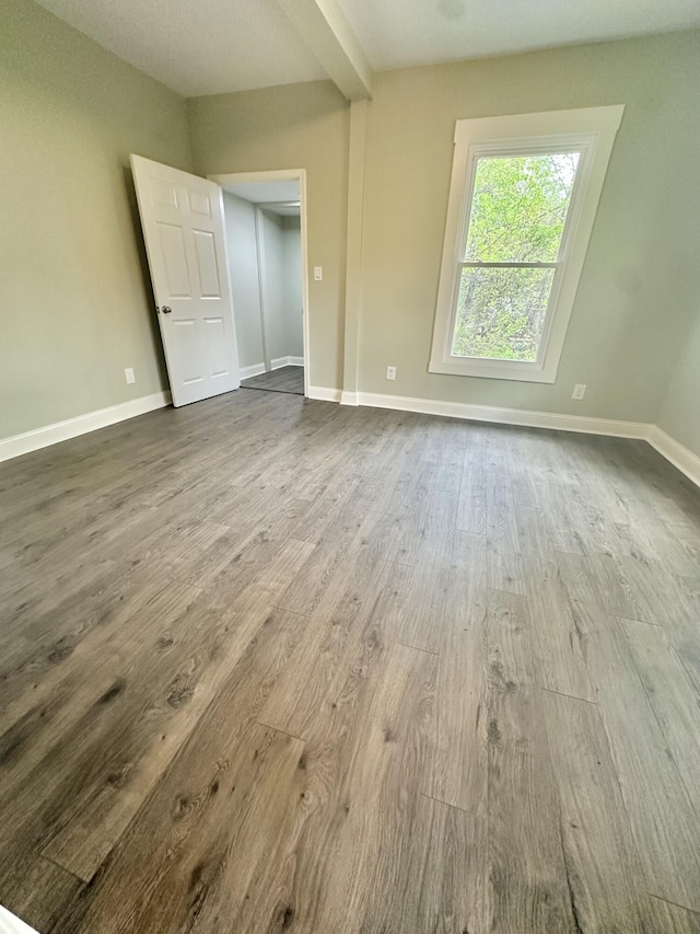 unfurnished bedroom with baseboards and dark wood-style floors