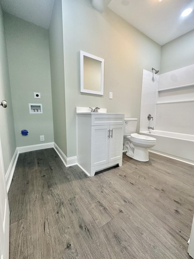bathroom with toilet, baseboards, wood finished floors, vanity, and tub / shower combination