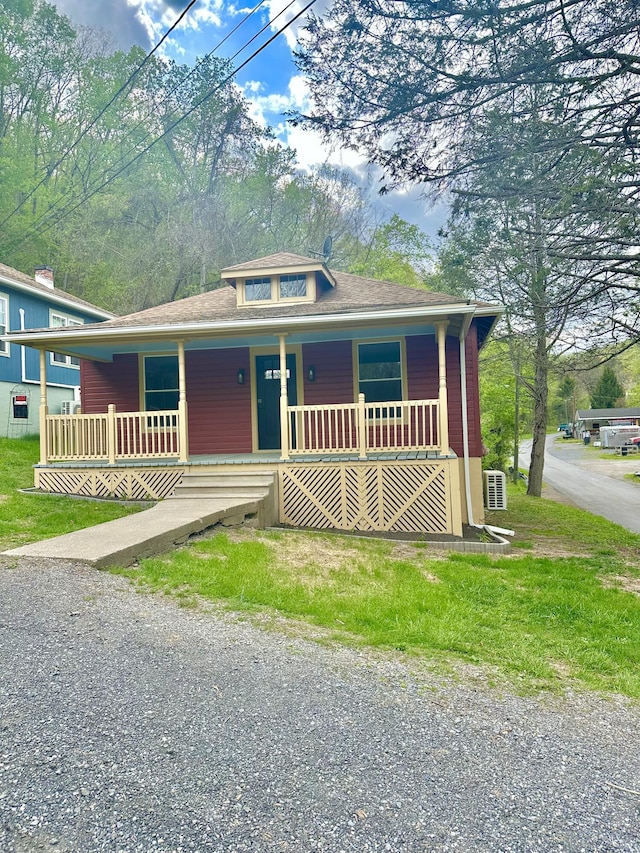 bungalow-style house featuring gravel driveway, a shingled roof, and covered porch