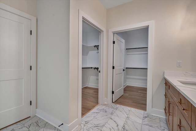 120 Pointe O Woods Dr, Huddleston, VA 24104 - bathroom featuring marble look tiles, vanity, a walk in closet, and baseboards