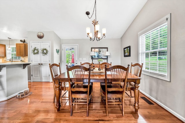 dining room with light wood-type flooring, visible vents, baseboards, and an inviting chandelier