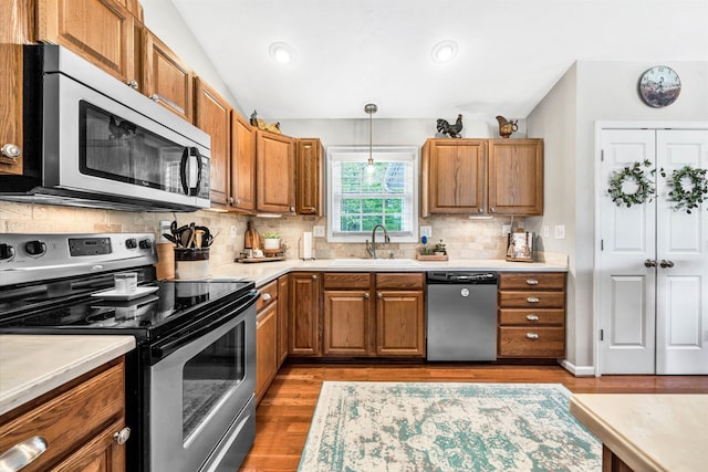 kitchen with stainless steel appliances, light countertops, a sink, and brown cabinetry