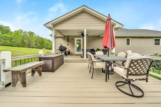 wooden deck with ceiling fan, outdoor dining area, and a yard