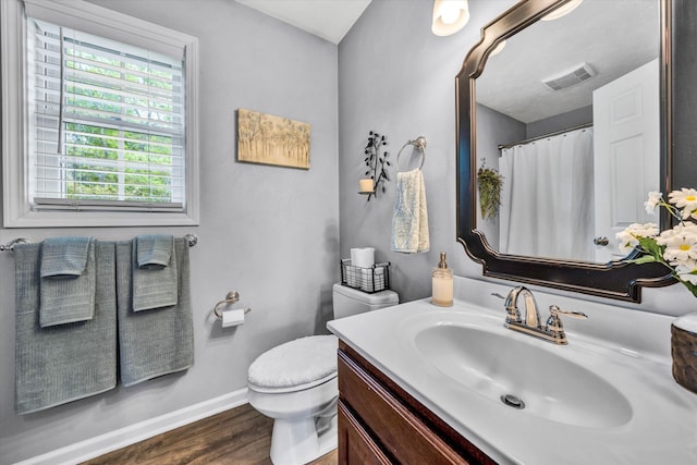 bathroom with wood finished floors, vanity, baseboards, toilet, and visible vents