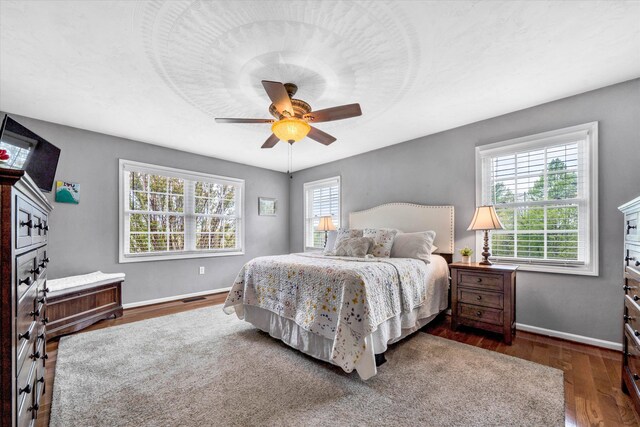 bedroom featuring visible vents, baseboards, a ceiling fan, and wood finished floors
