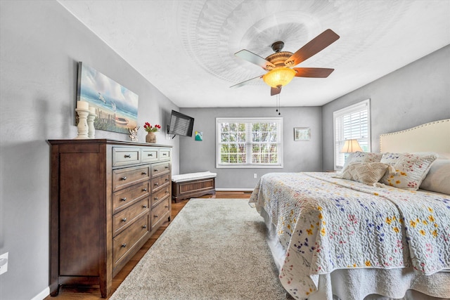 bedroom with wood finished floors, a ceiling fan, and baseboards