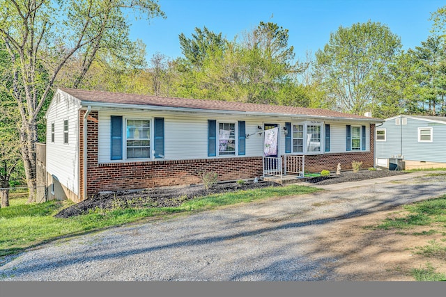 ranch-style house featuring brick siding, driveway, and fence