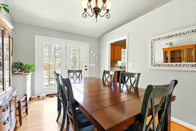 dining area featuring baseboards, an inviting chandelier, light wood-style floors, and a healthy amount of sunlight
