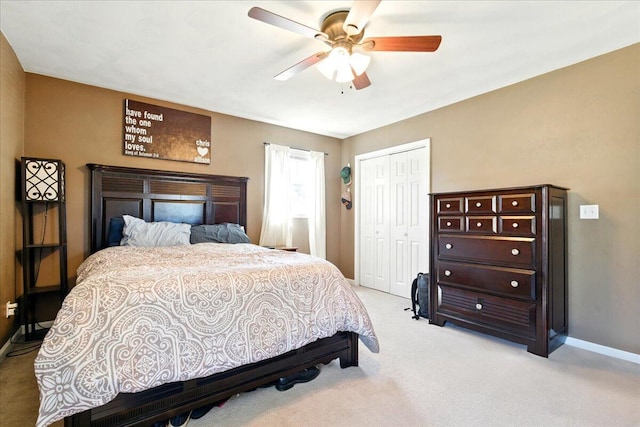 bedroom with light carpet, a closet, baseboards, and a ceiling fan