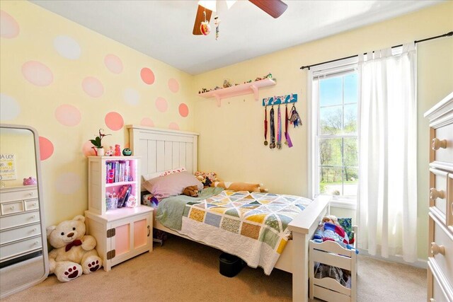 bedroom featuring light colored carpet, ceiling fan, and multiple windows