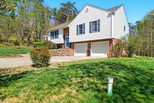 split foyer home with a garage, concrete driveway, a front lawn, and brick siding