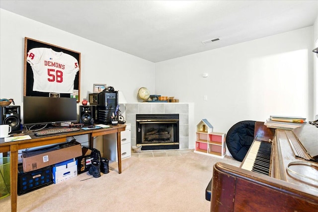 carpeted office space featuring a tiled fireplace and visible vents