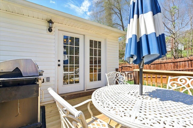 wooden deck with outdoor dining space, a grill, and fence