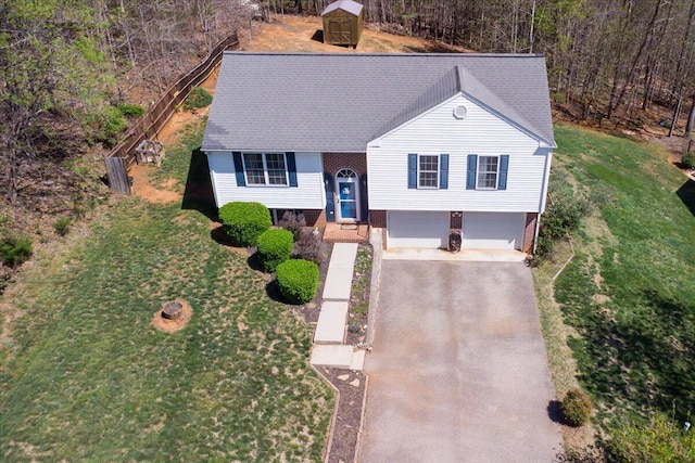 view of front of house with a front yard, roof with shingles, an attached garage, and aphalt driveway