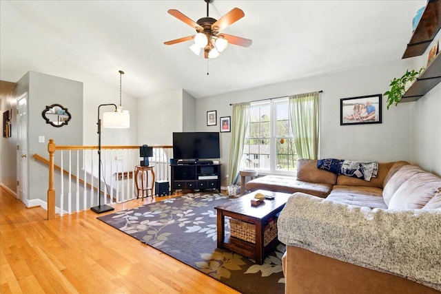 living area with ceiling fan, vaulted ceiling, wood finished floors, and baseboards