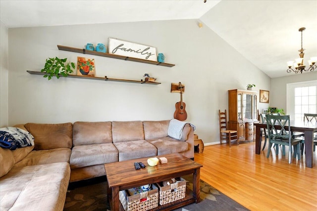 living area featuring light wood-style flooring, an inviting chandelier, and lofted ceiling