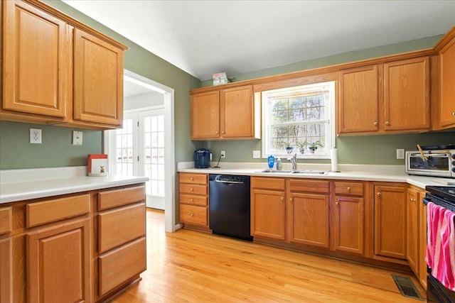 kitchen with visible vents, black dishwasher, a sink, light wood finished floors, and a toaster