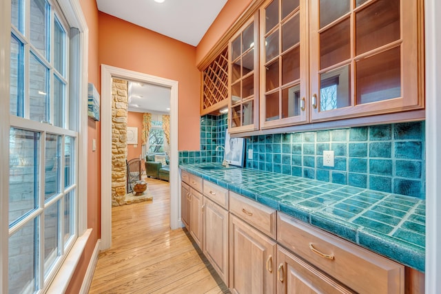 3649 Peakwood Dr SW, Roanoke, VA 24014 - kitchen featuring decorative backsplash, light wood-style flooring, glass insert cabinets, light brown cabinets, and tile countertops