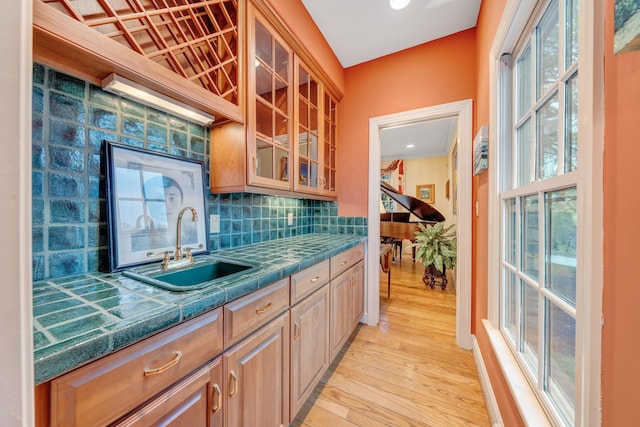3649 Peakwood Dr SW, Roanoke, VA 24014 - kitchen featuring light wood-style flooring, backsplash, glass insert cabinets, and tile counters