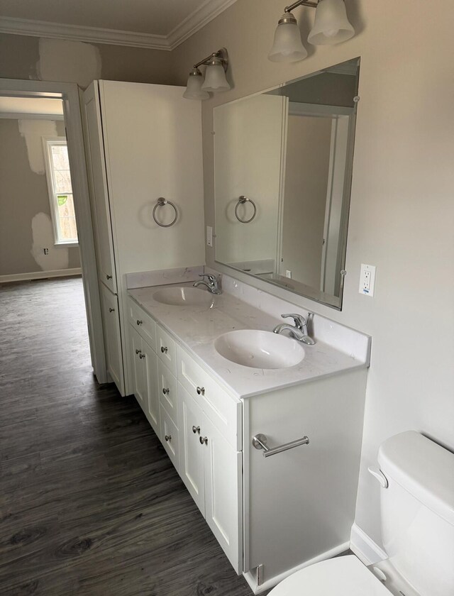 bathroom with toilet, a sink, ornamental molding, and wood finished floors