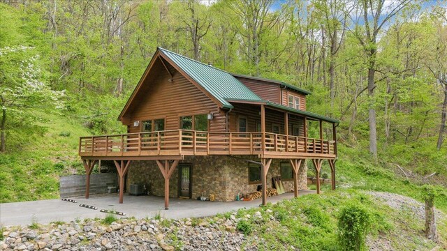 exterior space featuring a wooden deck, a view of trees, a patio, and cooling unit